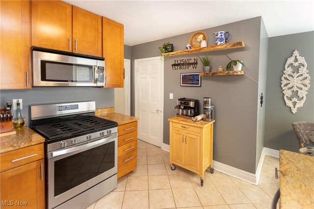 3678 Lynnfield Rd, Shaker Heights, OH 44122 - kitchen with appliances with stainless steel finishes, light tile patterned flooring, open shelves, brown cabinetry, and light stone counters