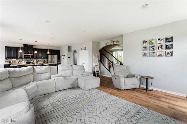 2979 Cloverhurst St NE, Canton, OH 44721 - living room with arched walkways, light wood finished floors, and stairs