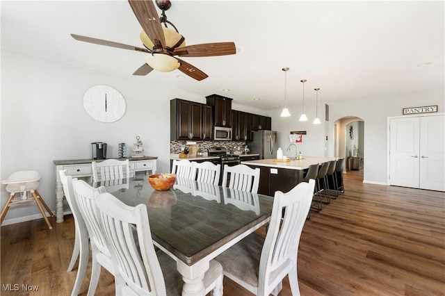2979 Cloverhurst St NE, Canton, OH 44721 - dining space featuring arched walkways, a ceiling fan, and dark wood-style floors