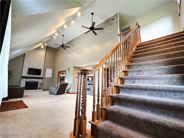 3585 Hayfield Rd, Dresden, OH 43821 - stairway featuring rail lighting, a ceiling fan, carpet, a fireplace, and high vaulted ceiling