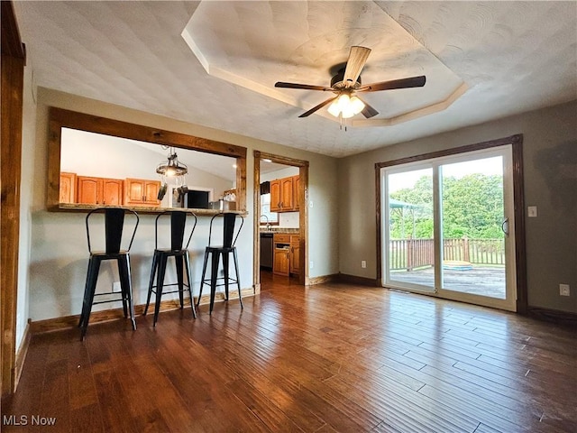 3585 Hayfield Rd, Dresden, OH 43821 - kitchen featuring a ceiling fan, dark wood-style flooring, brown cabinets, a kitchen breakfast bar, and a raised ceiling