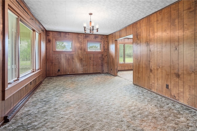 11861 Moffitt St SW, Massillon, OH 44647 - carpeted empty room with a chandelier, wooden walls, a baseboard heating unit, and baseboard heating