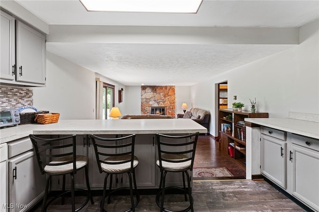 40698 Whitney Rd, Lagrange, OH 44050 - kitchen with a peninsula, a breakfast bar area, dark wood finished floors, a fireplace, and light countertops