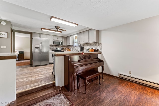 40698 Whitney Rd, Lagrange, OH 44050 - kitchen with stainless steel appliances, a peninsula, wood finished floors, a baseboard radiator, and backsplash