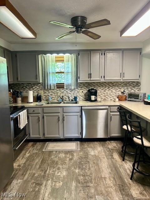 40698 Whitney Rd, Lagrange, OH 44050 - kitchen featuring appliances with stainless steel finishes, gray cabinets, wood-type flooring, and tasteful backsplash