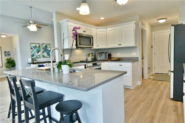 125 Fitch Blvd Unit 254, Youngstown, OH 44515 - kitchen featuring stainless steel appliances, white cabinets, a breakfast bar, light wood-style floors, and a ceiling fan