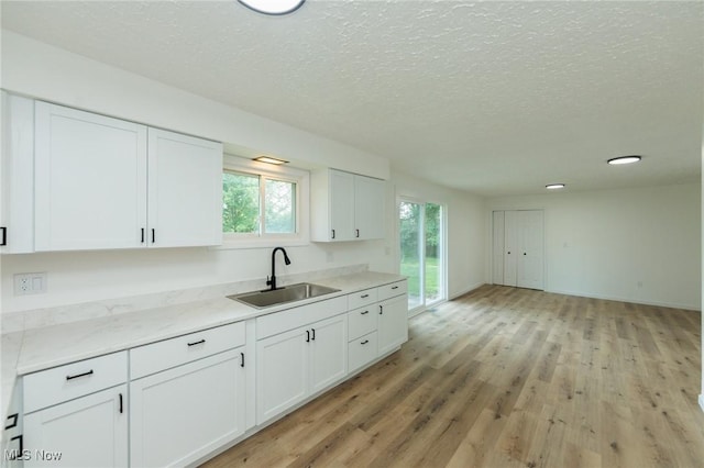 1730 W 20th St, Lorain, OH 44052 - kitchen featuring white cabinets, light wood-style flooring, a textured ceiling, and light stone counters