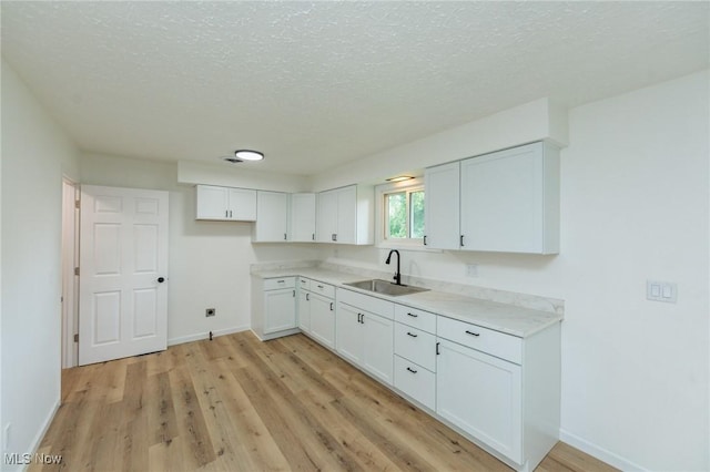 1730 W 20th St, Lorain, OH 44052 - kitchen with light wood-style flooring, light countertops, white cabinets, and a textured ceiling