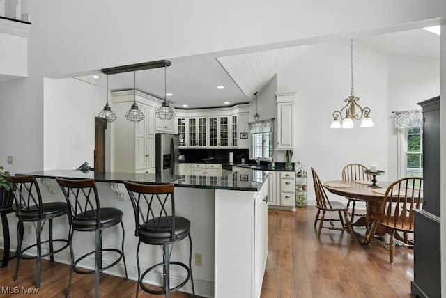 1497 Hunting Hollow Dr, Hudson, OH 44236 - kitchen with stainless steel fridge with ice dispenser, a breakfast bar, vaulted ceiling, glass insert cabinets, and dark wood-style floors