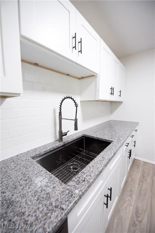 8507 Akins Rd Unit C-2, North Royalton, OH 44133 - kitchen featuring white cabinetry, light wood-style flooring, decorative backsplash, and light stone countertops