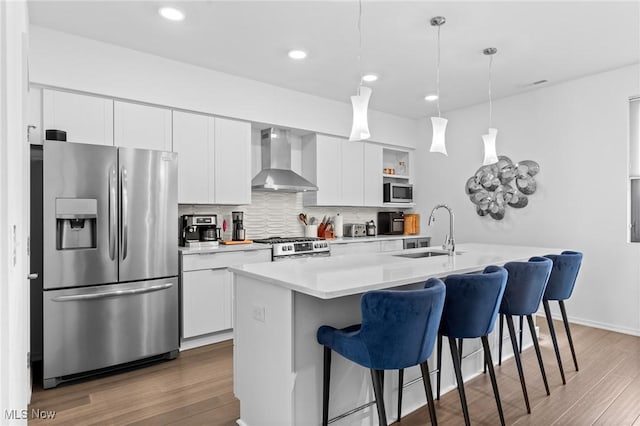 2317 Scranton Rd, Cleveland, OH 44113 - kitchen with stainless steel appliances, wall chimney exhaust hood, a breakfast bar, an island with sink, and white cabinetry