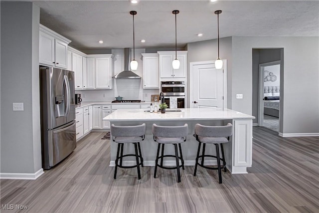 23797 St Andrews Dr, Columbia Station, OH 44028 - kitchen with appliances with stainless steel finishes, wall chimney range hood, wood finished floors, white cabinetry, and recessed lighting