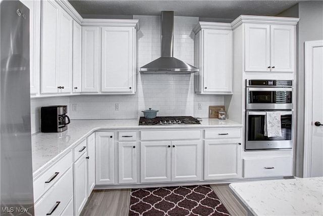 23797 St Andrews Dr, Columbia Station, OH 44028 - kitchen featuring wall chimney range hood, appliances with stainless steel finishes, white cabinets, and decorative backsplash