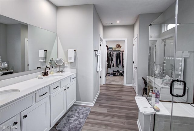 23797 St Andrews Dr, Columbia Station, OH 44028 - bathroom featuring double vanity, a stall shower, a spacious closet, wood finished floors, and recessed lighting