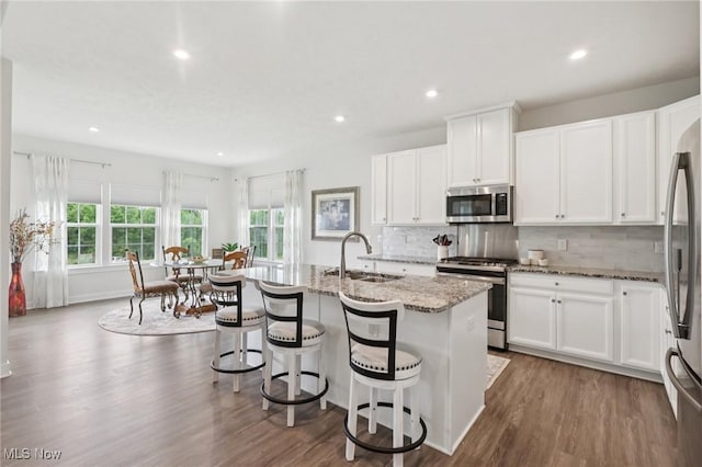 8488 Raya Ln, Streetsboro, OH 44241 - kitchen featuring stainless steel appliances, decorative backsplash, light stone counters, recessed lighting, and a kitchen island with sink