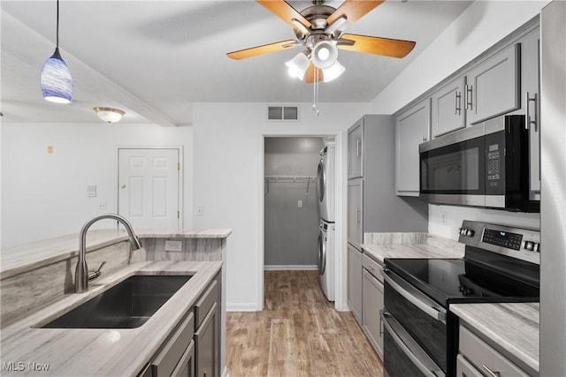 23004 Chandlers Ln Unit 107, Olmsted Falls, OH 44138 - kitchen featuring appliances with stainless steel finishes, stacked washer / dryer, gray cabinetry, a ceiling fan, and light wood-style floors