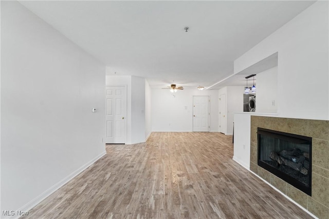 23004 Chandlers Ln Unit 107, Olmsted Falls, OH 44138 - unfurnished living room featuring wood finished floors, a tiled fireplace, washer / dryer, and a ceiling fan