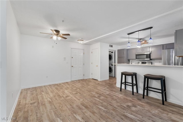 23004 Chandlers Ln Unit 107, Olmsted Falls, OH 44138 - kitchen with appliances with stainless steel finishes, stacked washer / drying machine, gray cabinetry, a ceiling fan, and light wood-type flooring