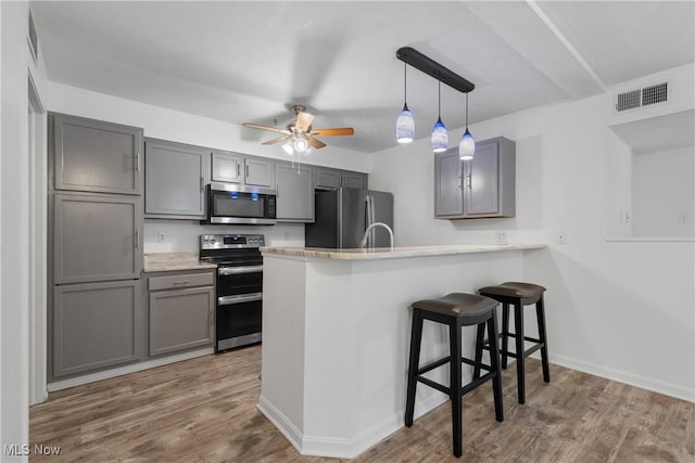 23004 Chandlers Ln Unit 107, Olmsted Falls, OH 44138 - kitchen with appliances with stainless steel finishes, gray cabinetry, a peninsula, and wood finished floors
