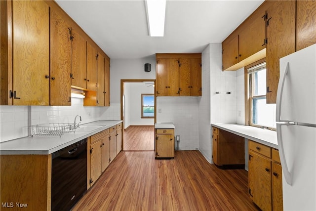 10808 Park Heights Ave, Garfield Heights, OH 44125 - kitchen featuring dishwasher, freestanding refrigerator, wood finished floors, tasteful backsplash, and brown cabinets