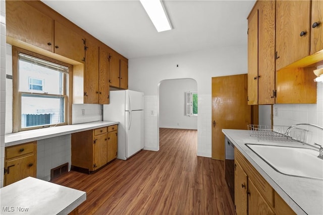 10808 Park Heights Ave, Garfield Heights, OH 44125 - kitchen with freestanding refrigerator, brown cabinets, light countertops, dark wood-type flooring, and backsplash