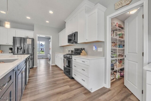 13196 Barrington Dr, Grafton, OH 44044 - kitchen featuring appliances with stainless steel finishes, light wood-type flooring, recessed lighting, white cabinetry, and decorative backsplash