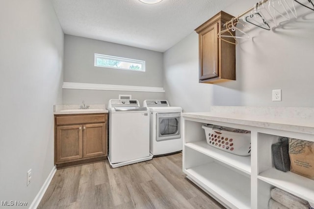 13196 Barrington Dr, Grafton, OH 44044 - washroom featuring cabinet space, separate washer and dryer, light wood-style floors, and a textured ceiling