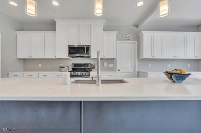 13196 Barrington Dr, Grafton, OH 44044 - kitchen featuring appliances with stainless steel finishes, white cabinetry, decorative backsplash, hanging light fixtures, and recessed lighting