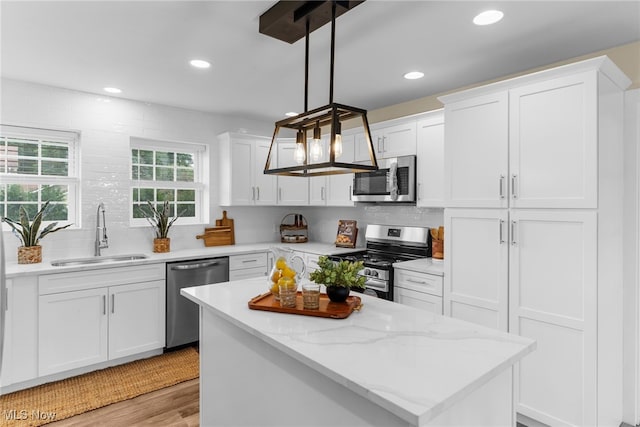 381 Lauretta Ln, Hubbard, OH 44425 - kitchen with appliances with stainless steel finishes, white cabinets, tasteful backsplash, light wood-style floors, and a kitchen island