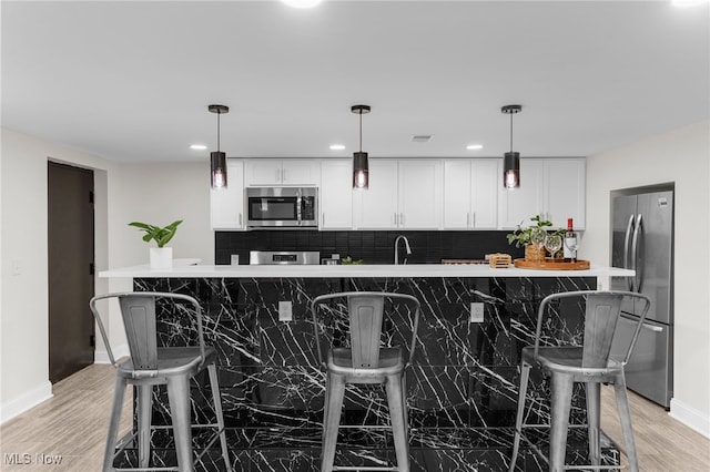 381 Lauretta Ln, Hubbard, OH 44425 - kitchen with appliances with stainless steel finishes, decorative backsplash, light wood-type flooring, white cabinets, and hanging light fixtures