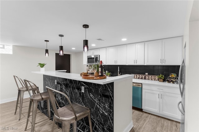 381 Lauretta Ln, Hubbard, OH 44425 - kitchen with dishwasher, stainless steel microwave, white cabinetry, decorative backsplash, and a kitchen breakfast bar