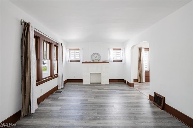 1145 Herberich Ave, Akron, OH 44301 - unfurnished living room featuring wood finished floors, arched walkways, and a fireplace