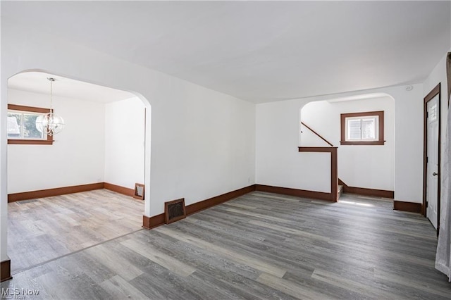 1145 Herberich Ave, Akron, OH 44301 - empty room featuring arched walkways, plenty of natural light, wood finished floors, and a chandelier