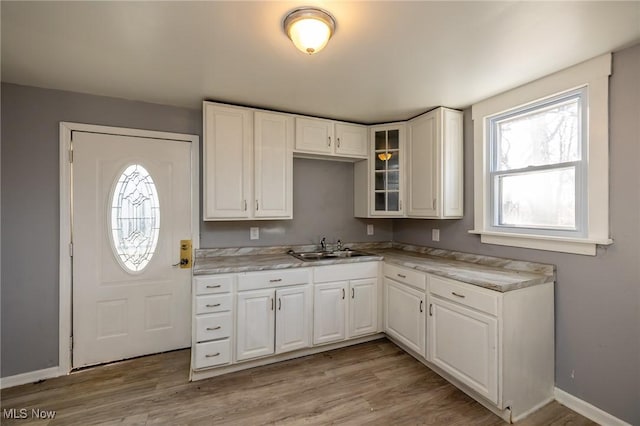3888 W 37th St, Cleveland, OH 44109 - kitchen featuring white cabinets, glass insert cabinets, light countertops, and light wood-type flooring