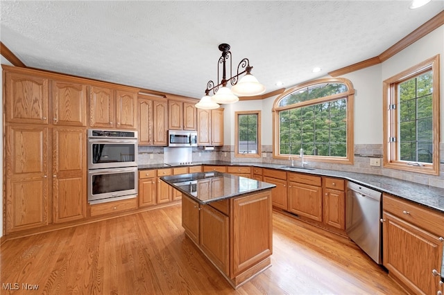 4035 Evergreen Ln, Richfield, OH 44286 - kitchen with appliances with stainless steel finishes, crown molding, light wood-style floors, a center island, and tasteful backsplash