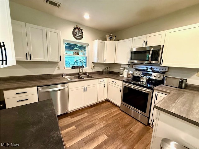 1550 Swift Rd, Waterford, OH 45786 - kitchen featuring stainless steel appliances, dark countertops, white cabinets, wood finished floors, and recessed lighting