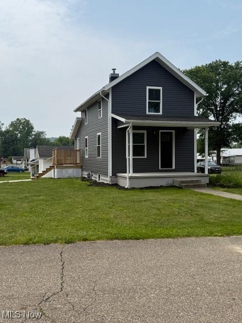 637 Maple St, Newcomerstown, OH 43832 - view of side of property with a chimney, a lawn, and a porch