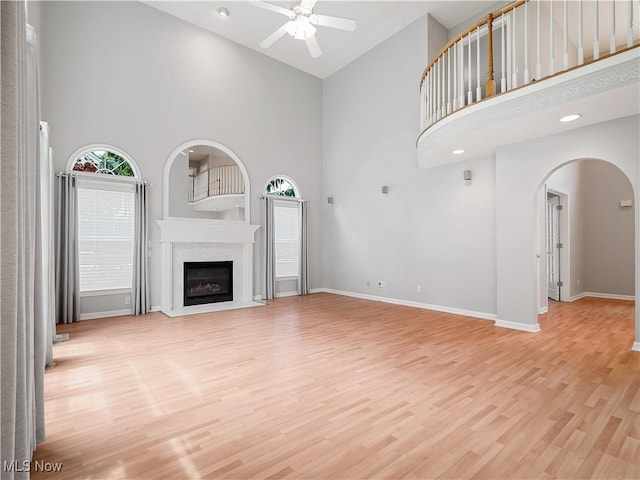 32969 Durrell Ave, Avon Lake, OH 44012 - unfurnished living room with high vaulted ceiling, ceiling fan, arched walkways, light wood-type flooring, and a premium fireplace
