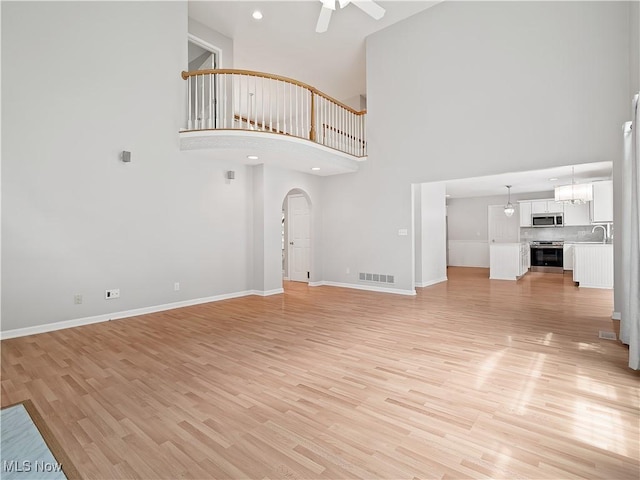 32969 Durrell Ave, Avon Lake, OH 44012 - unfurnished living room with a ceiling fan, a high ceiling, light wood-style floors, and arched walkways