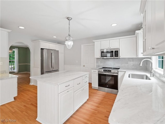 32969 Durrell Ave, Avon Lake, OH 44012 - kitchen with appliances with stainless steel finishes, arched walkways, a center island, white cabinetry, and light wood finished floors