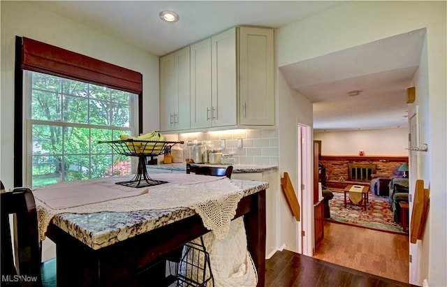 27008 Sweetbriar Dr, North Olmsted, OH 44070 - kitchen with dark wood-type flooring, light stone counters, backsplash, recessed lighting, and a kitchen bar