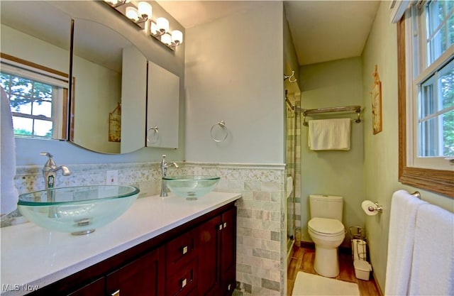 27008 Sweetbriar Dr, North Olmsted, OH 44070 - bathroom featuring plenty of natural light, a stall shower, tile walls, double vanity, and wainscoting