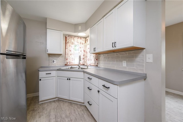810 Indian Trl, Akron, OH 44314 - kitchen with freestanding refrigerator, light wood-type flooring, white cabinetry, tasteful backsplash, and light countertops