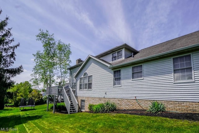 6202 Rockside Cir NW, Canton, OH 44718 - view of side of home with a trampoline, stairway, a yard, a wooden deck, and a chimney