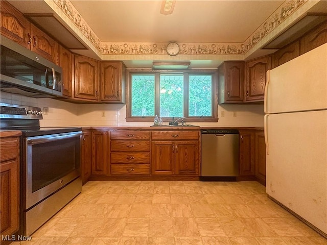 2178 Hewitt Gifford Rd SW, Warren, OH 44481 - kitchen with appliances with stainless steel finishes, brown cabinetry, light floors, and tasteful backsplash