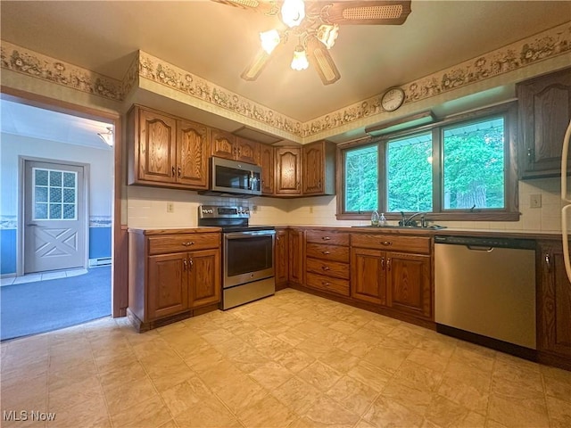 2178 Hewitt Gifford Rd SW, Warren, OH 44481 - kitchen with stainless steel appliances, brown cabinetry, light floors, ceiling fan, and baseboard heating