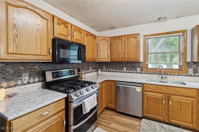 1012 Woodland Chase, Grafton, OH 44044 - kitchen featuring stainless steel appliances, light wood-style floors, tasteful backsplash, brown cabinets, and a textured ceiling