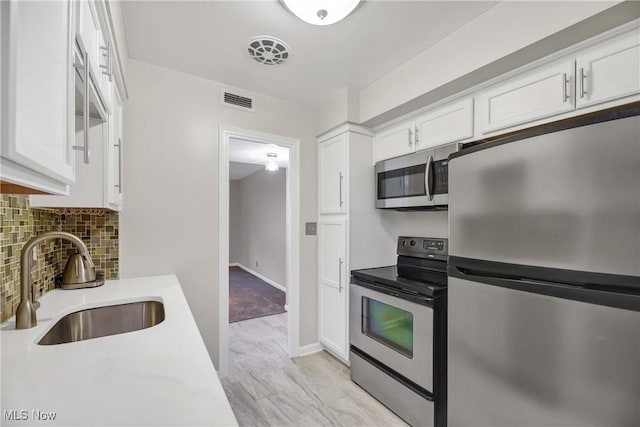 15875 Van Aken Blvd Unit 101C, Shaker Heights, OH 44120 - kitchen featuring stainless steel appliances, white cabinetry, decorative backsplash, and light countertops