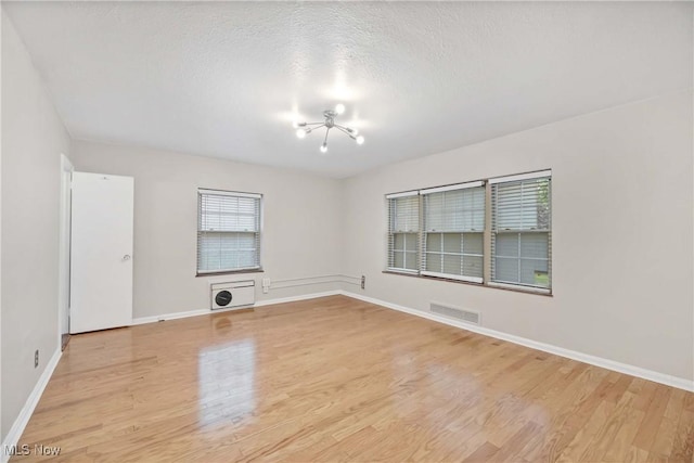 15875 Van Aken Blvd Unit 101C, Shaker Heights, OH 44120 - spare room featuring a chandelier, light wood-type flooring, and a textured ceiling