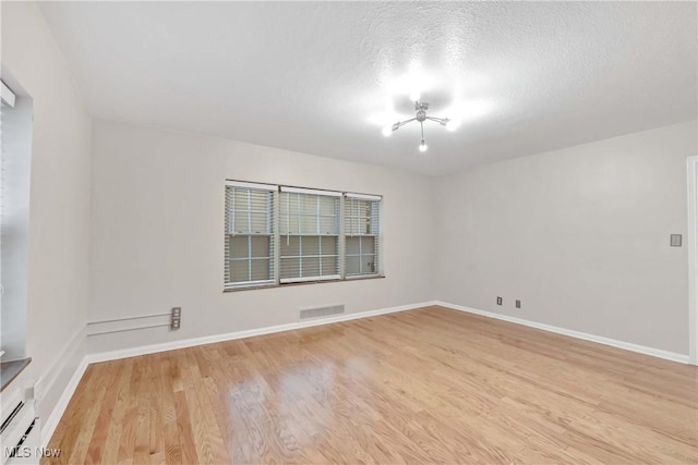 15875 Van Aken Blvd Unit 101C, Shaker Heights, OH 44120 - unfurnished room with a baseboard radiator, light wood-type flooring, and a textured ceiling